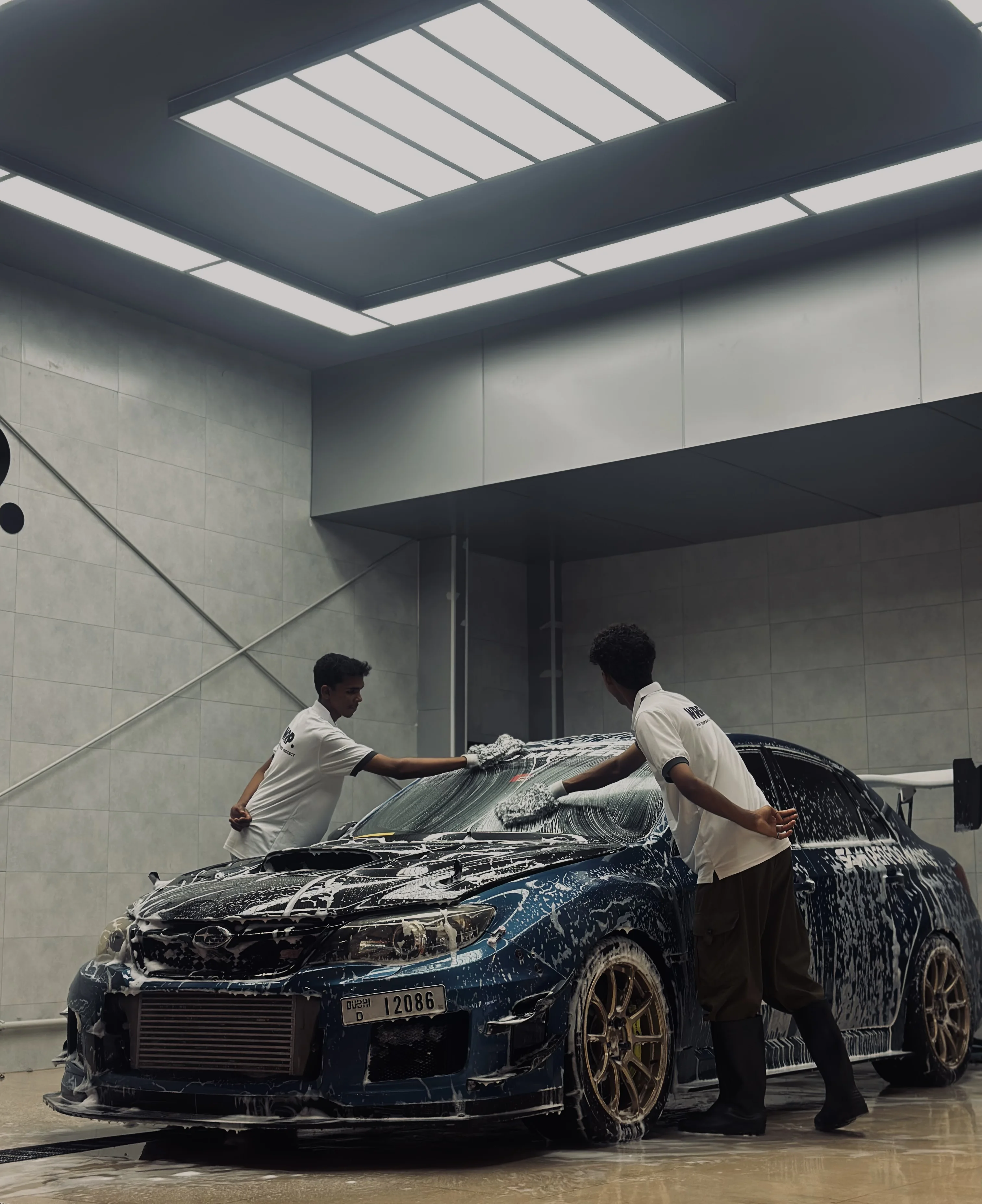 WRP Dubai team performing premium hand car wash with foam treatment on Subaru WRX STI